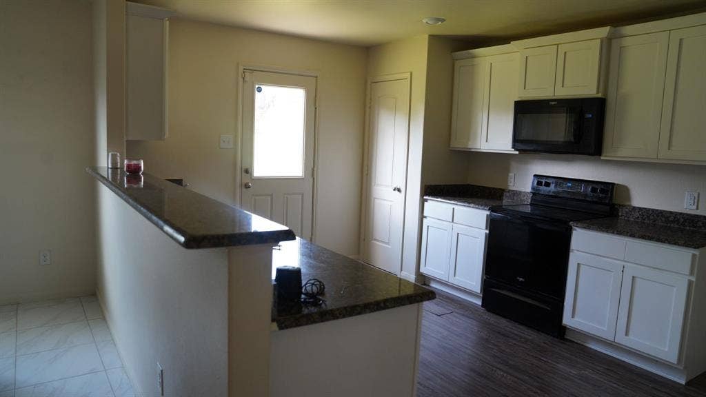 1321 Eagle Lake Drive, Azle, TX 76020 Kitchen featuring white shaker-style cabinetry, dark speckled countertops, black appliances, and wood-finish flooring