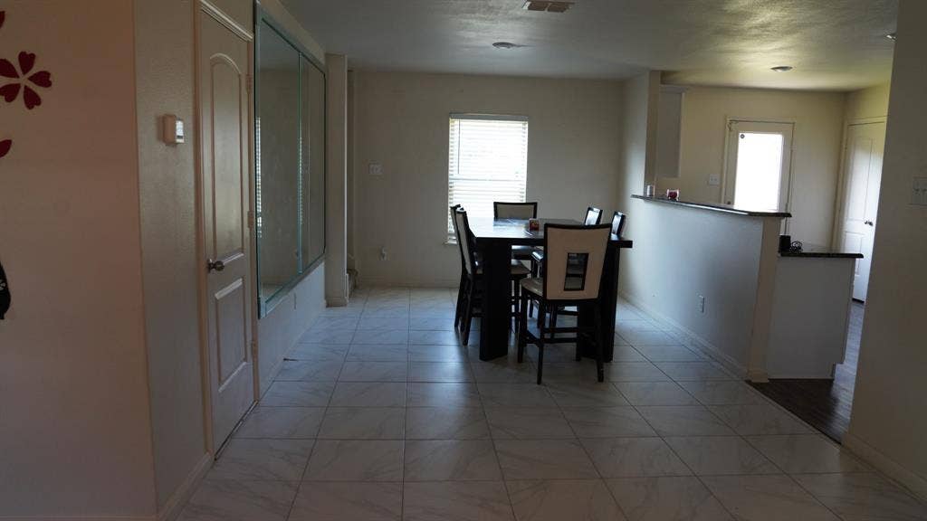 1321 Eagle Lake Drive, Azle, TX 76020 Spacious interior featuring light-toned tile flooring, a half-wall counter with a dark countertop, and a large window with blinds