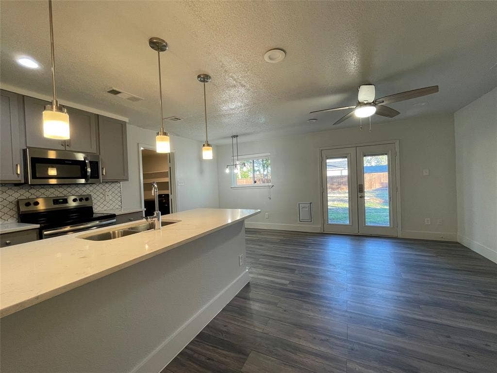 822 Johnnie Row, Seagoville, TX 75159 Kitchen with gray cabinetry, backsplash, dark hardwood / wood-style flooring, light stone countertops, and stainless steel appliances