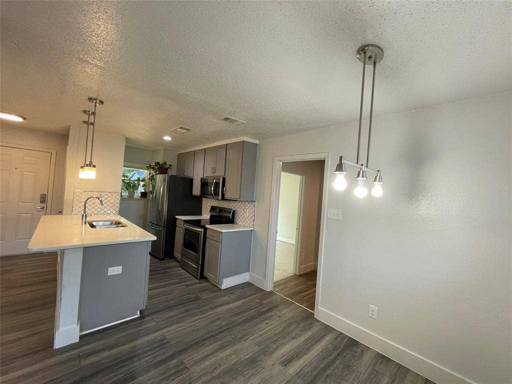 822 Johnnie Row, Seagoville, TX 75159 Kitchen featuring sink, decorative backsplash, appliances with stainless steel finishes, decorative light fixtures, and dark hardwood / wood-style flooring