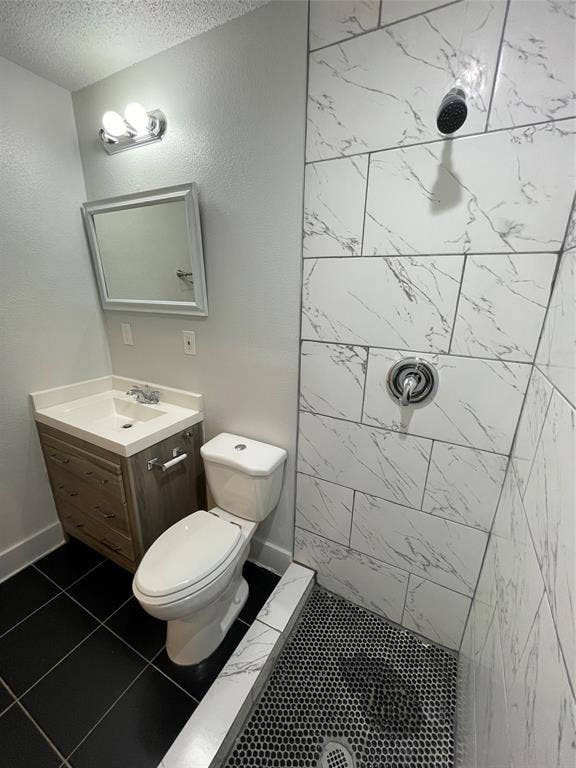 822 Johnnie Row, Seagoville, TX 75159 Bathroom with a tile shower, a textured ceiling, tile patterned floors, vanity, and toilet