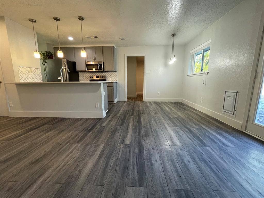 822 Johnnie Row, Seagoville, TX 75159 Unfurnished living room with a textured ceiling and dark wood-type flooring