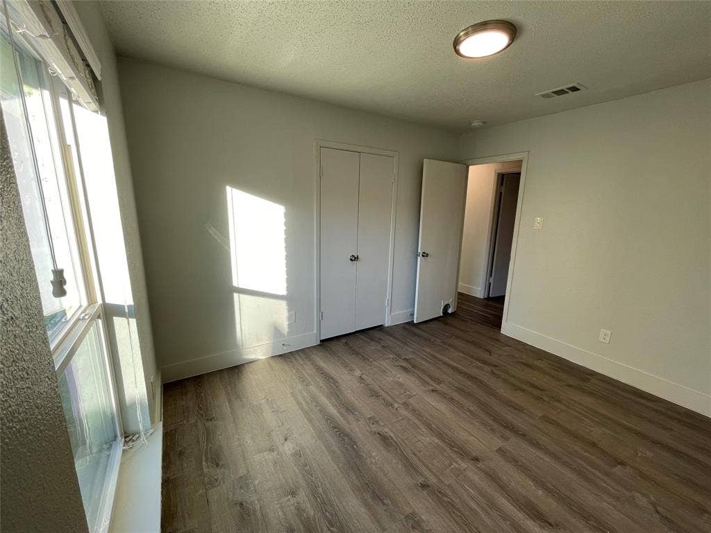 822 Johnnie Row, Seagoville, TX 75159 Unfurnished bedroom with hardwood / wood-style flooring, a closet, and a textured ceiling