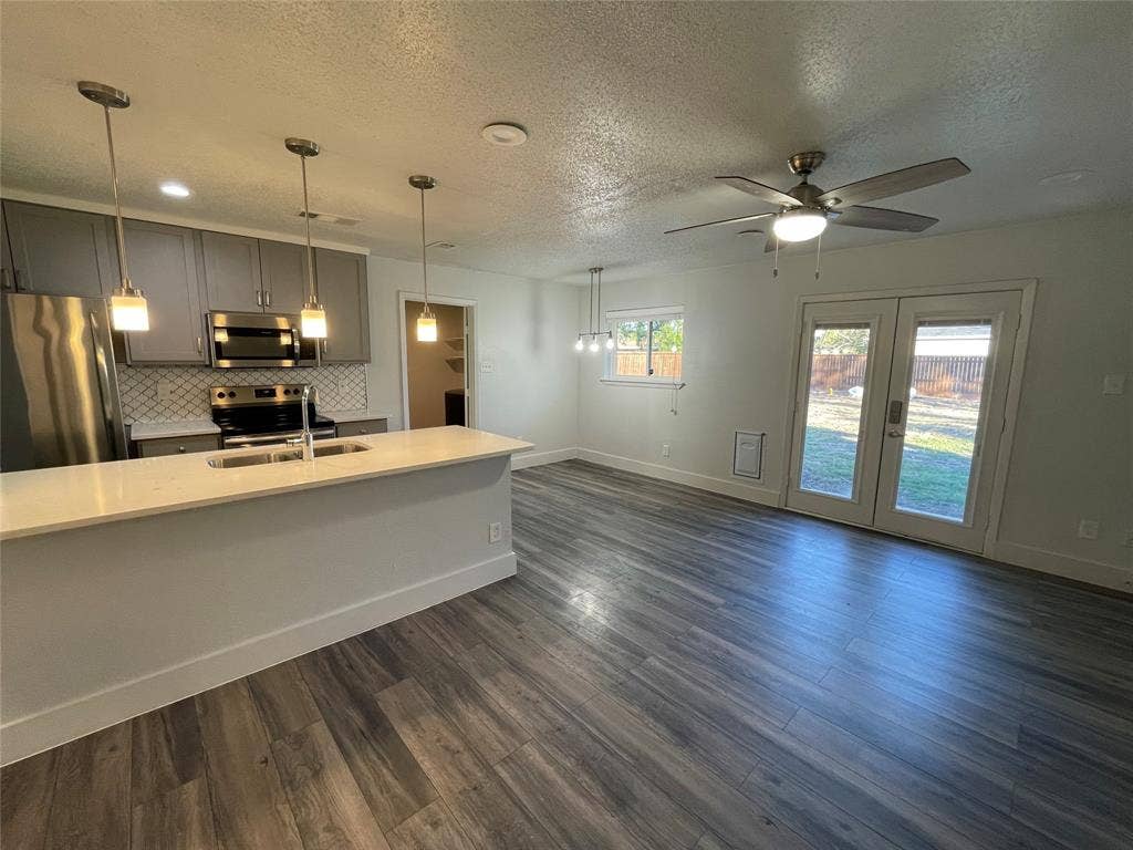 822 Johnnie Row, Seagoville, TX 75159 Kitchen with dark hardwood / wood-style floors, pendant lighting, stainless steel appliances, and ceiling fan