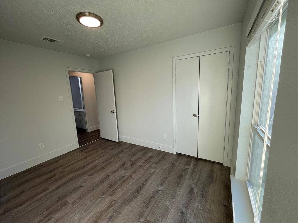 822 Johnnie Row, Seagoville, TX 75159 Unfurnished bedroom featuring a textured ceiling, dark wood-type flooring, and a closet