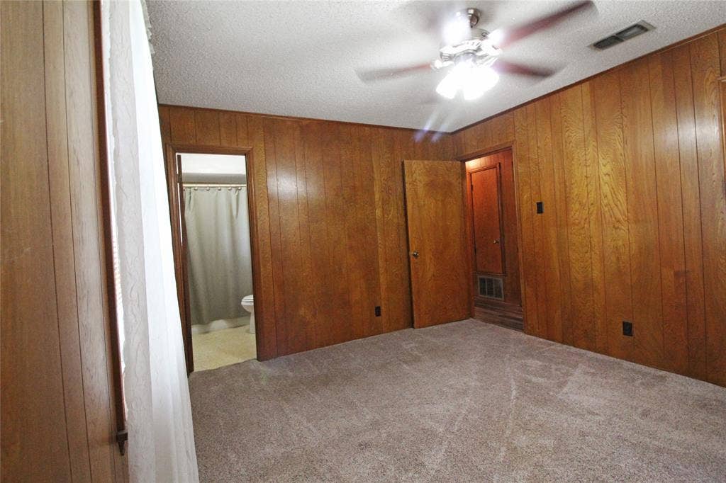 8769 S Fm 148, Scurry, TX 75158 Interior room featuring wood paneling walls, a ceiling fan with light fixture, and textured carpet flooring