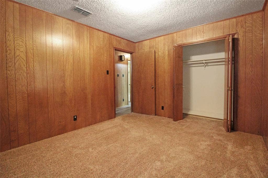 8769 S Fm 148, Scurry, TX 75158 Room with wood paneling, plush carpeting, and a built-in closet with double bi-fold doors