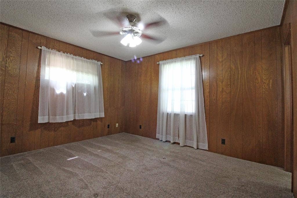 8769 S Fm 148, Scurry, TX 75158 Room featuring wood paneling, a textured ceiling, and neutral carpet flooring