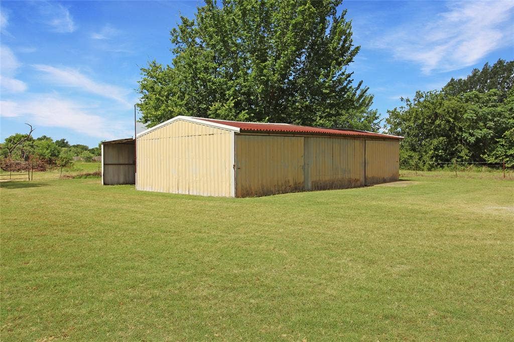 8769 S Fm 148, Scurry, TX 75158 Corrugated metal building with a red roof, featuring an attached lean-to structure