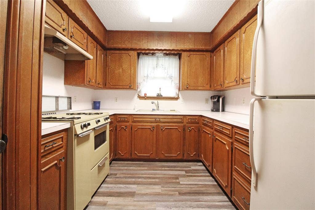 8769 S Fm 148, Scurry, TX 75158 Kitchen featuring extensive wood cabinetry, white countertops, a built-in gas range, a white refrigerator, and wood-finish flooring