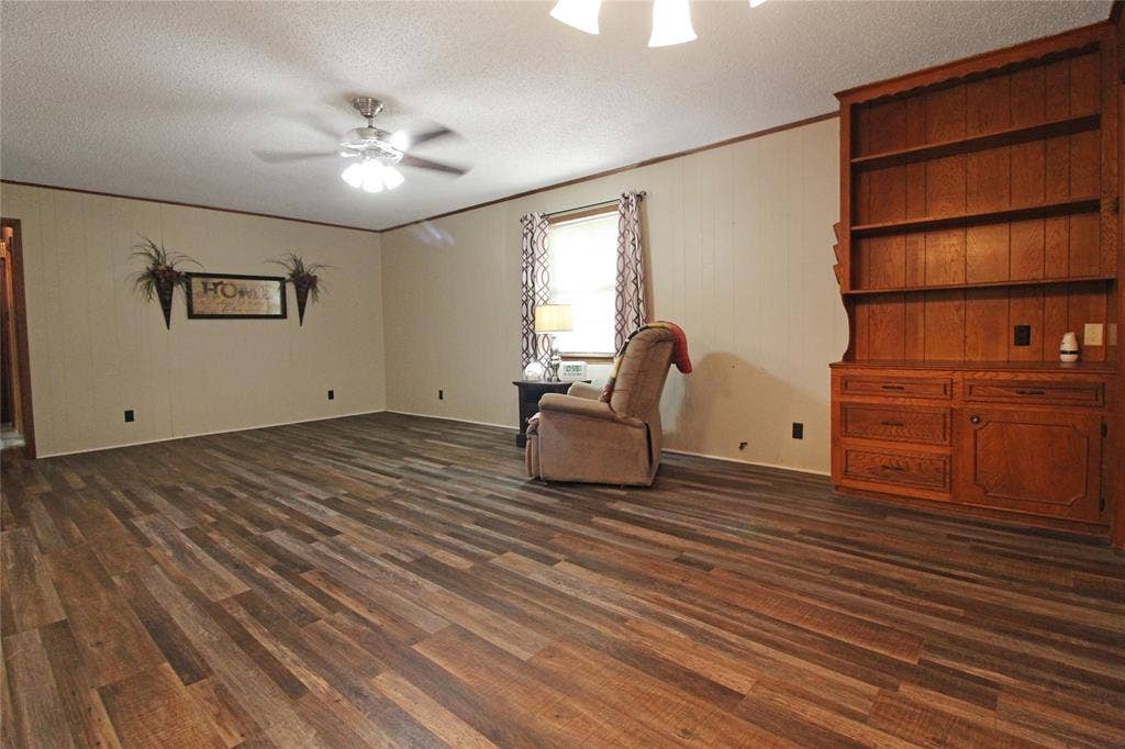 8769 S Fm 148, Scurry, TX 75158 Spacious room featuring multi-tone wood-finish flooring and a ceiling fan with integrated lighting