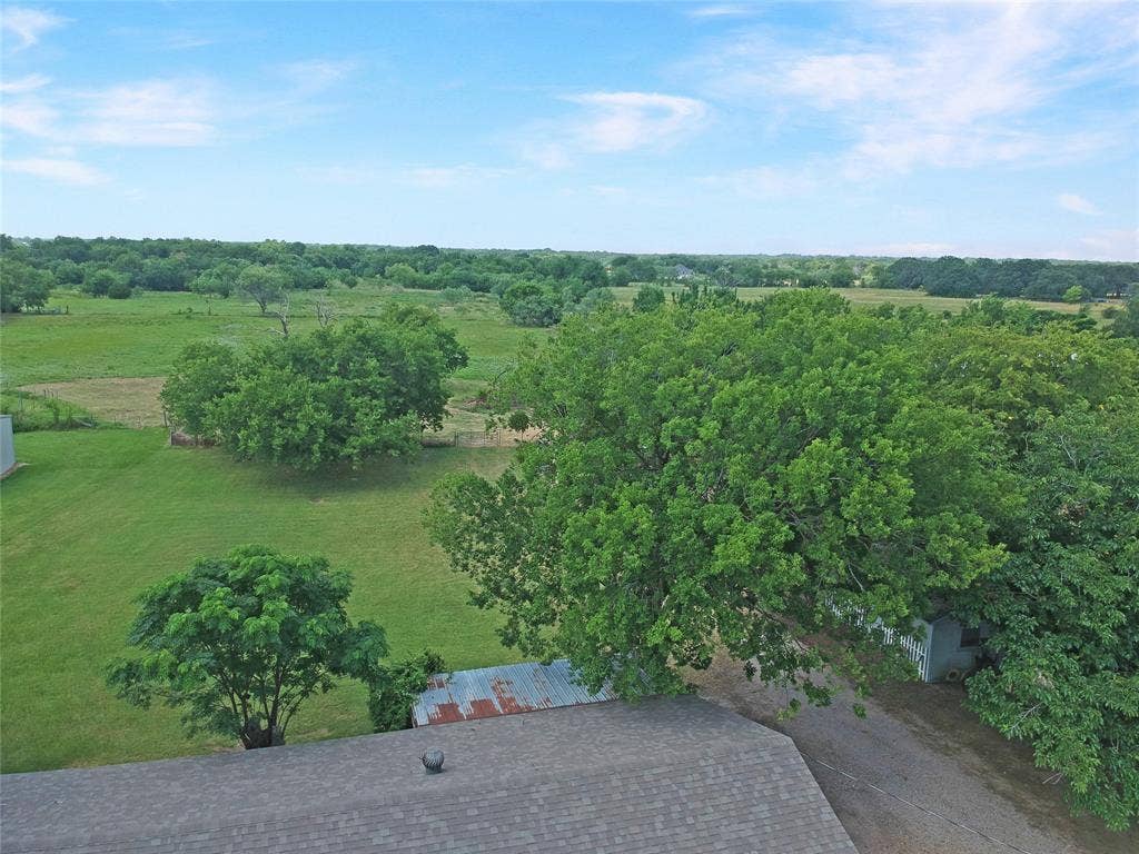 8769 S Fm 148, Scurry, TX 75158 Expansive green landscape featuring mature trees, open fields, and a gravel drive