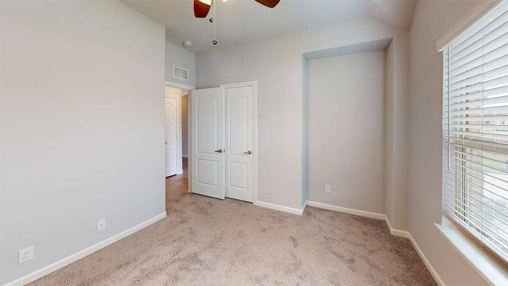 Bedroom featuring neutral-toned carpet flooring, light gray wall paint, a built-in recessed wall niche, and a window with white blinds