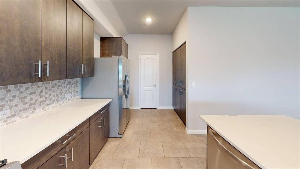 Kitchen featuring dark wood-finish cabinetry, light-toned countertops, and a honeycomb-patterned tile backsplash