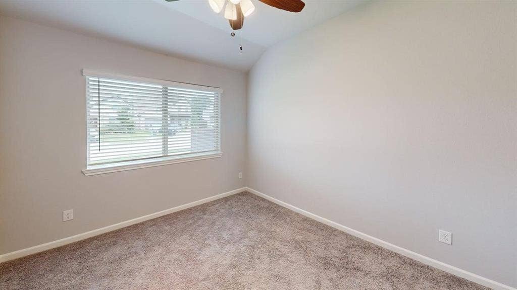 Room featuring a window with blinds, vaulted ceilings, a ceiling fan, and plush carpet flooring