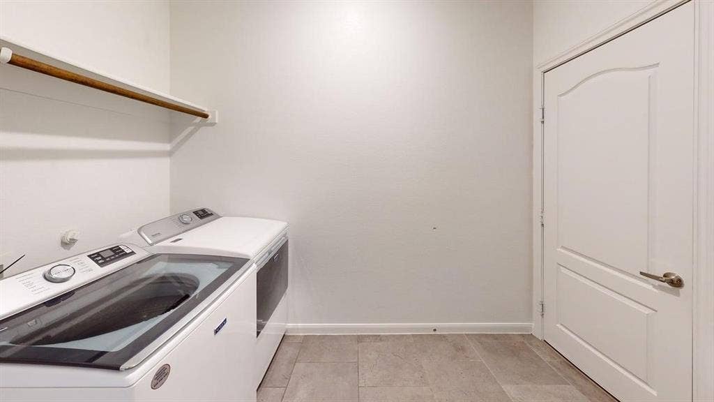 Laundry area featuring a built-in shelf with a hanging rod, tile flooring, and a paneled interior door with brushed nickel hardware