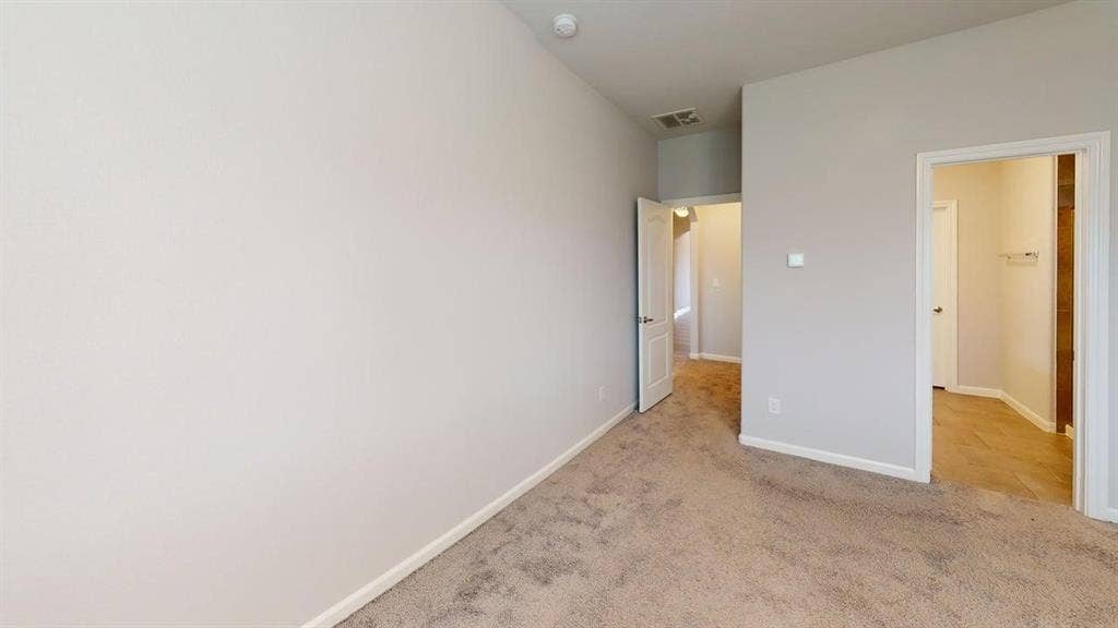 Carpeted room with light neutral wall tones and white baseboards