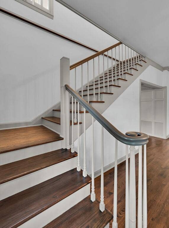 2825 Lake Air Drive, Waco, TX 76710 Staircase featuring wood-finish treads and risers, a white baluster system, and a dark handrail with a decorative scroll newel post