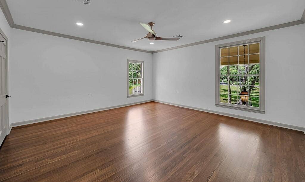 2825 Lake Air Drive, Waco, TX 76710 Spacious room featuring wood-finish flooring, two large windows with exterior views, crown molding, a ceiling fan, and recessed lighting
