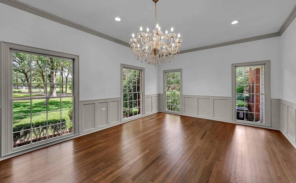2825 Lake Air Drive, Waco, TX 76710 Hardwood flooring throughout this spacious room, featuring neutral wall paint, wainscoting, and crown molding