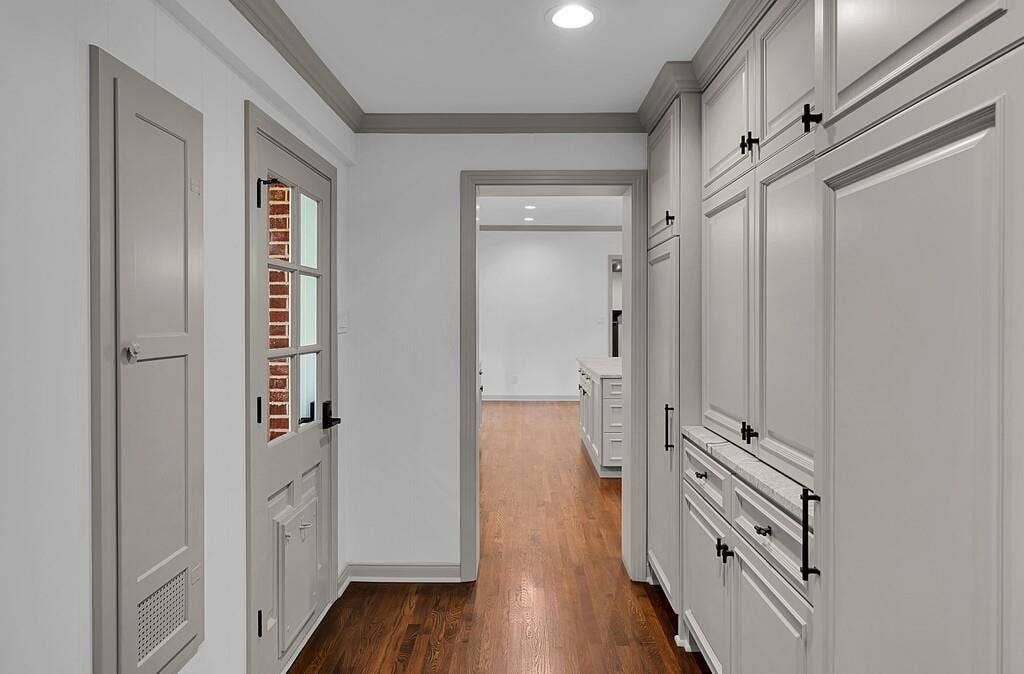 2825 Lake Air Drive, Waco, TX 76710 Hardwood flooring throughout, showcasing extensive built-in cabinetry with black hardware, recessed lighting, and a paneled door with glass inserts