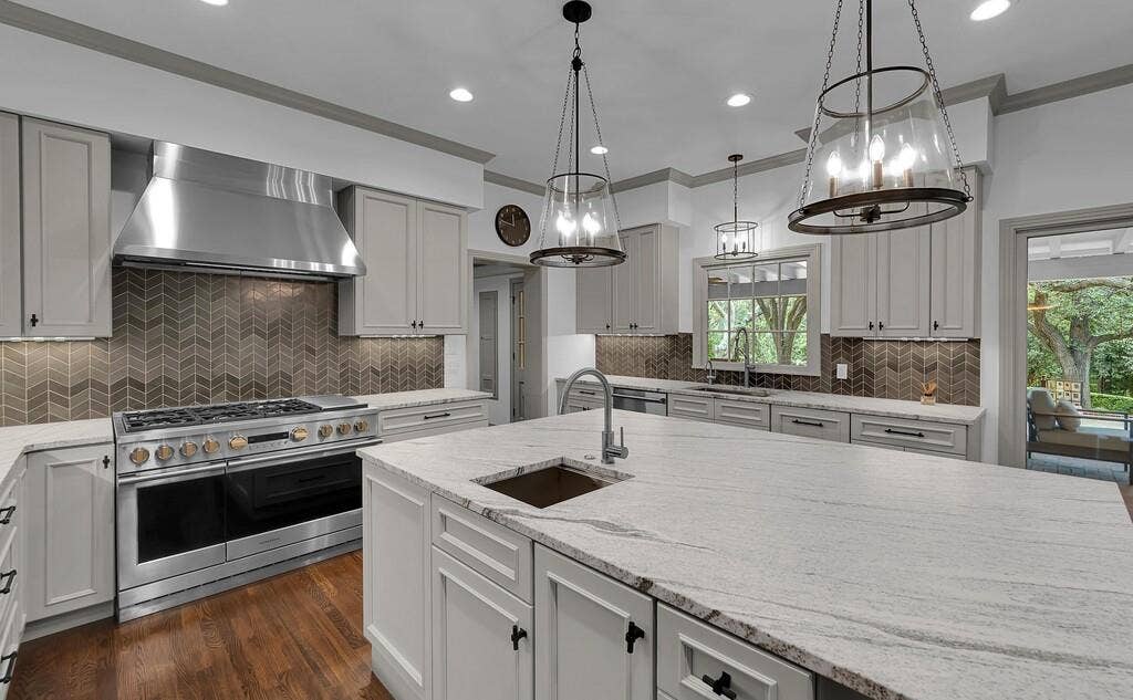 2825 Lake Air Drive, Waco, TX 76710 Gourmet kitchen featuring a large central island with an undermount sink, light-toned countertops, and custom cabinetry with dark hardware