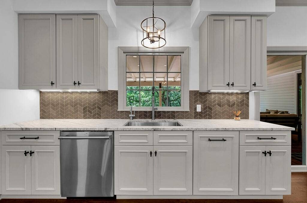 2825 Lake Air Drive, Waco, TX 76710 Kitchen space featuring light-colored cabinetry with dark hardware, a stainless steel sink, and a stainless steel dishwasher