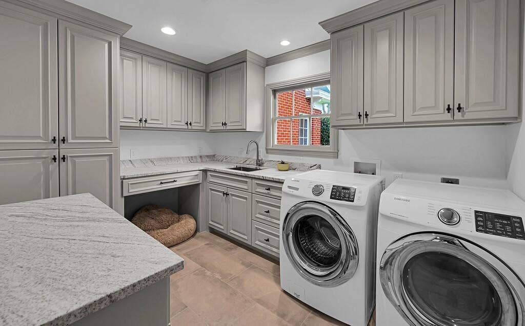 2825 Lake Air Drive, Waco, TX 76710 Laundry room featuring extensive built-in cabinetry, solid surface countertops, an undermount sink with a gooseneck faucet, and tile flooring