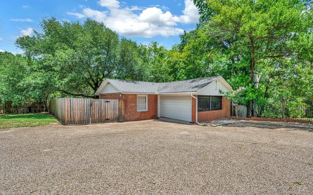 2825 Lake Air Drive, Waco, TX 76710 Brick exterior building with a single garage door, white trim, and a shingle roof