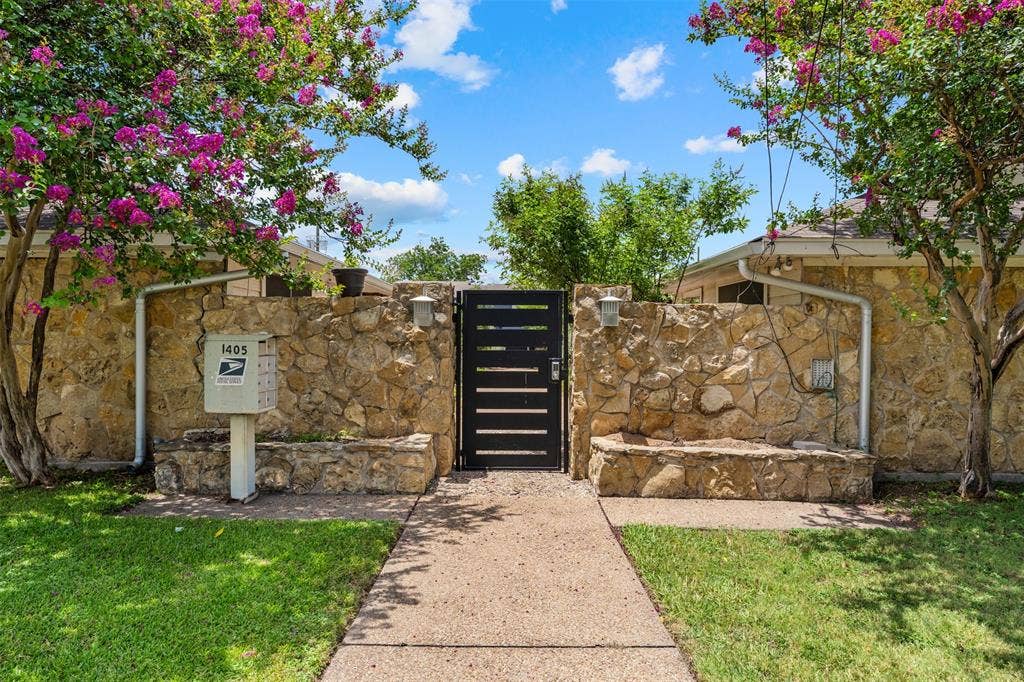 1405 Speight Avenue, #1, Waco, TX 76706 Stone privacy wall with integrated stone bench seating, a black slatted gate, and a concrete pathway