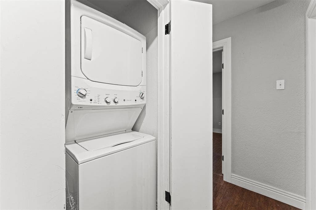 1405 Speight Avenue, #1, Waco, TX 76706 Laundry closet featuring a white stacked washer and dryer, painted white walls, and wood-finish flooring