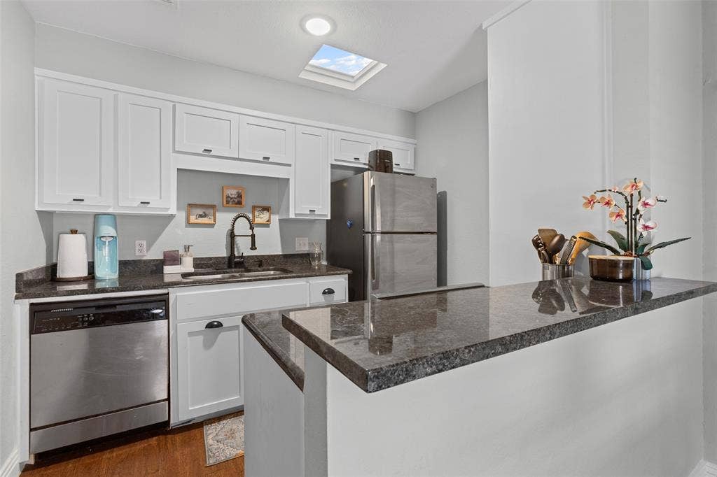 1405 Speight Avenue, #1, Waco, TX 76706 Kitchen featuring white cabinetry, dark granite countertops, stainless steel appliances, a bar-height counter, and a skylight