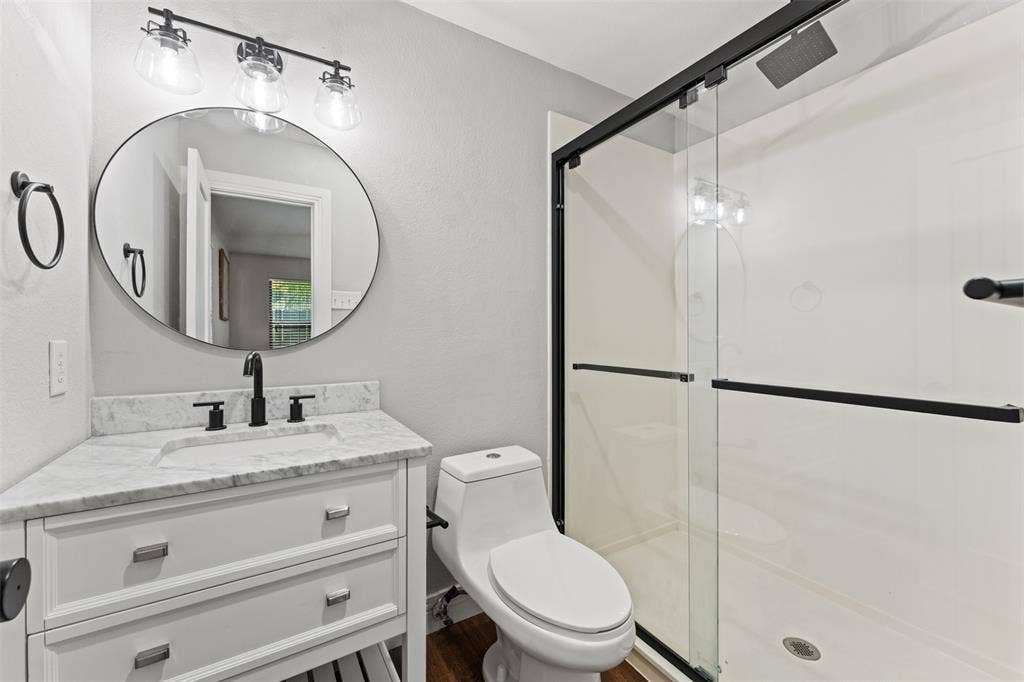 1405 Speight Avenue, #1, Waco, TX 76706 Bathroom featuring a white vanity with a light-toned countertop, a contemporary round mirror, and a matte black three-light fixture