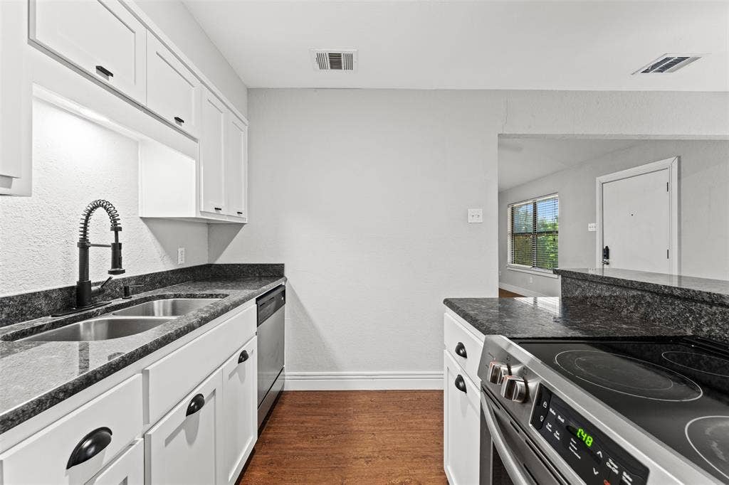 1405 Speight Avenue, #1, Waco, TX 76706 Kitchen featuring white cabinetry, dark stone countertops, stainless steel appliances, and wood-finish flooring