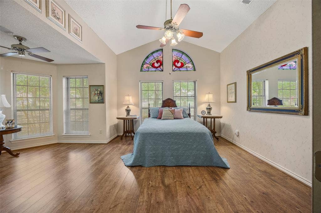 205 Covey Lane, McKinney, TX 75071 Vaulted ceiling room featuring wood-finish flooring, multiple windows, and decorative stained-glass arch windows