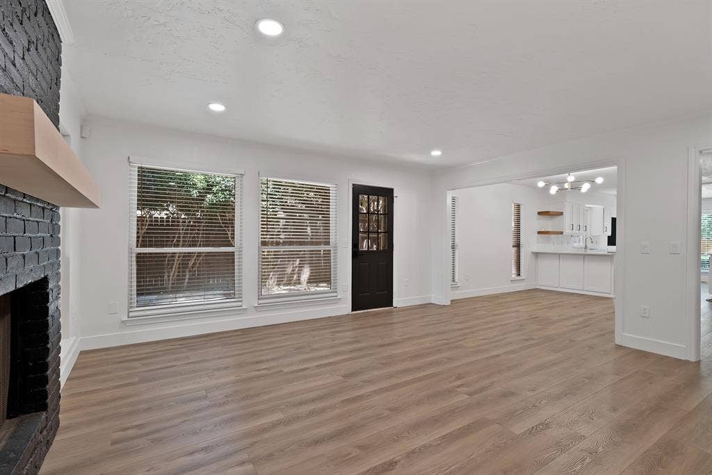 4021 San Mateo Drive, Plano, TX 75093 Spacious living area featuring light wood-finish flooring, a painted brick fireplace with a wood mantel, and recessed lighting