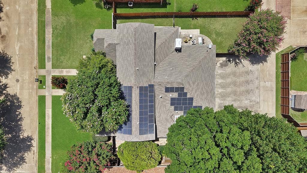 4021 San Mateo Drive, Plano, TX 75093 Residential property featuring a shingled roof, multiple solar panel arrays, and a concrete patio
