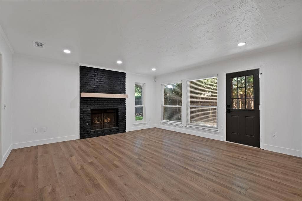 4021 San Mateo Drive, Plano, TX 75093 Living space featuring wood-finish flooring, a black brick fireplace with a light wood mantel, recessed lighting, and multiple windows with blinds