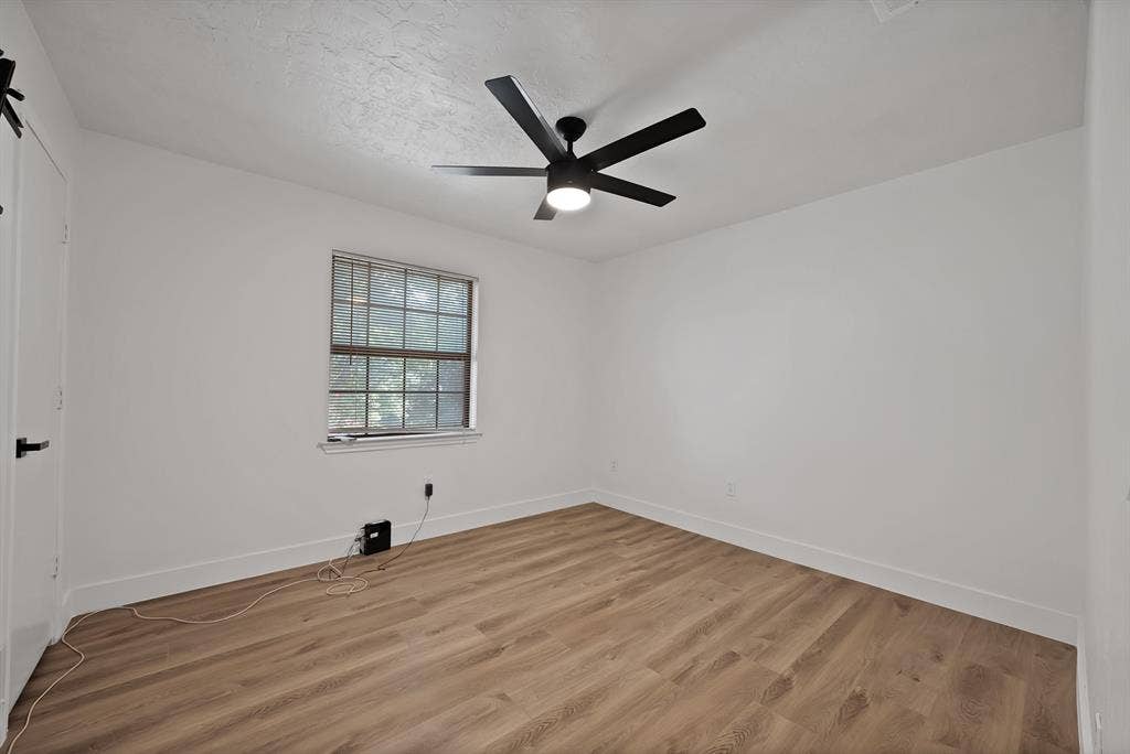 4021 San Mateo Drive, Plano, TX 75093 Bright room featuring wood-finish flooring, a contemporary ceiling fan with integrated lighting, a double-hung window, and a white interior door with matte black hardware