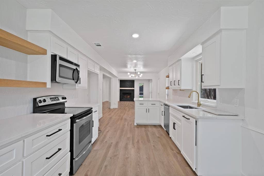 4021 San Mateo Drive, Plano, TX 75093 Contemporary kitchen featuring white shaker cabinetry, stainless steel appliances, light wood-finish flooring, and white countertops