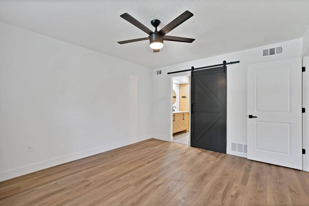 4021 San Mateo Drive, Plano, TX 75093 Spacious room featuring wood-finish flooring, white walls, and a black ceiling fan with integrated lighting
