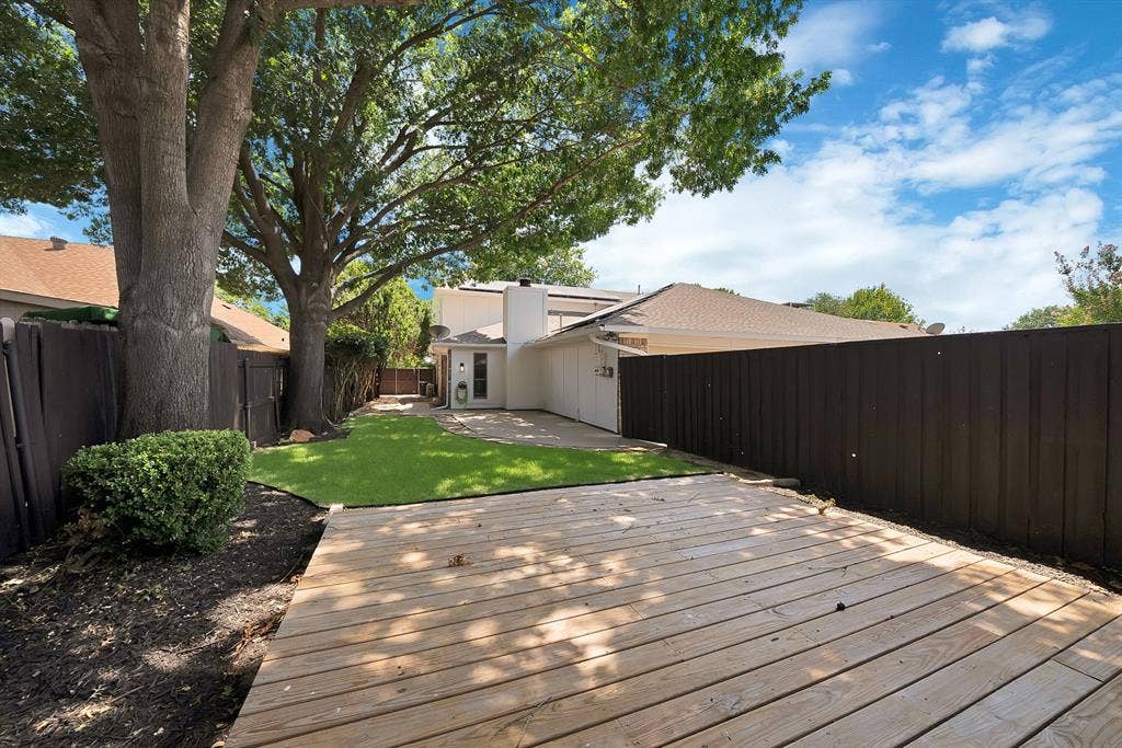 4021 San Mateo Drive, Plano, TX 75093 Expansive backyard featuring a wood deck, artificial turf, and mature trees providing natural shade