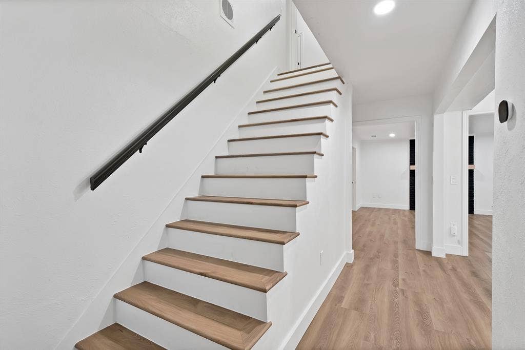 4021 San Mateo Drive, Plano, TX 75093 Staircase featuring wood-finish treads and white risers with a black wall-mounted handrail