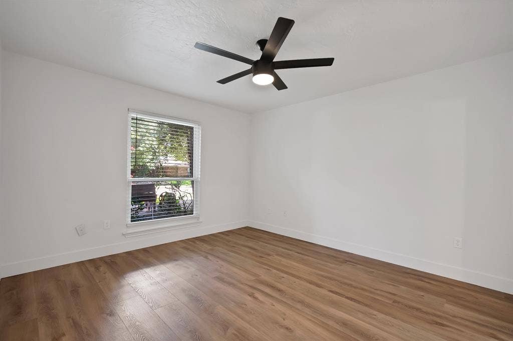 4021 San Mateo Drive, Plano, TX 75093 Spacious room featuring wood-finish flooring, a contemporary black ceiling fan with integrated lighting, and a window with horizontal blinds