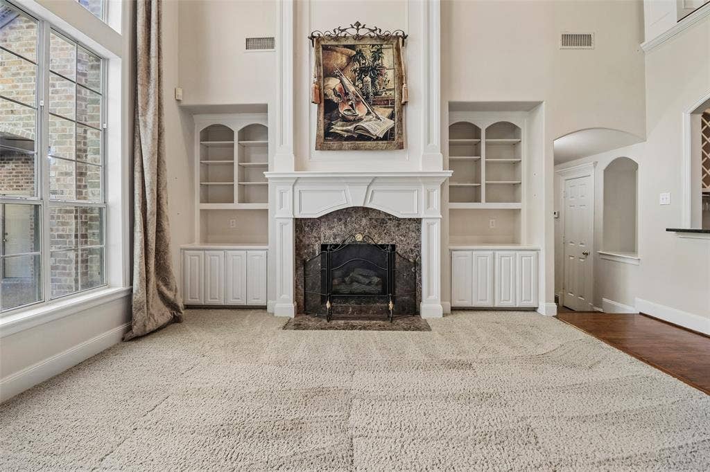 2600 Saratoga, McKinney, TX 75070 Formal living space featuring a fireplace with a stone surround, built-in shelving, white cabinetry, and large windows