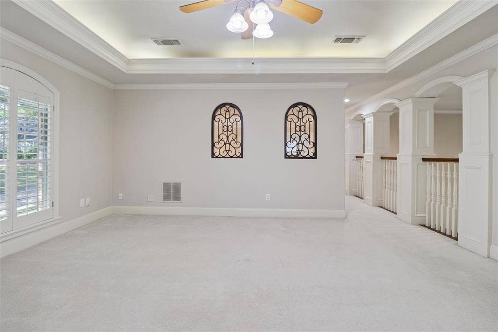 2600 Saratoga, McKinney, TX 75070 Tray ceiling with recessed lighting, ceiling fan, arched window with plantation shutters, decorative wrought iron accents, and a hallway featuring arched openings