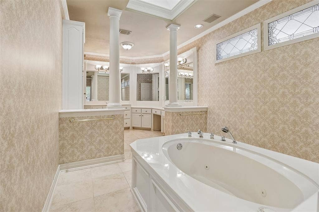 2600 Saratoga, McKinney, TX 75070 Built-in jetted tub with polished chrome fixtures, column accents, decorative transom windows, custom vanity cabinetry, and tiled flooring