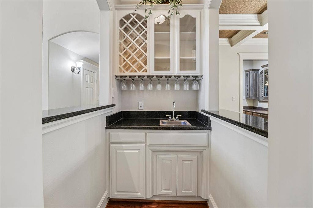 2600 Saratoga, McKinney, TX 75070 Built-in wet bar with white cabinetry, dark stone countertops, stainless steel sink, and integrated wine storage