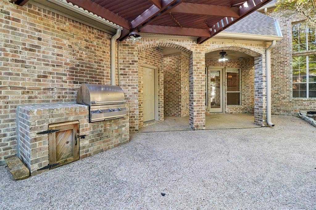 2600 Saratoga, McKinney, TX 75070 Brick exterior with a covered patio, built-in stainless steel grill, and an arched entryway