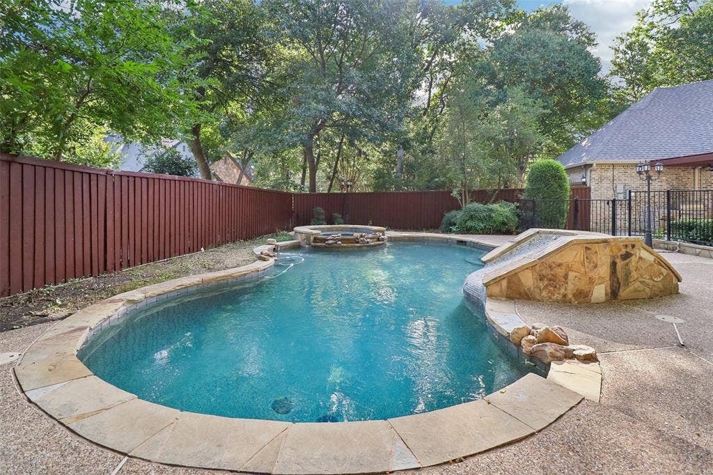 2600 Saratoga, McKinney, TX 75070 Curved swimming pool with an integrated hot tub and stone-clad water feature